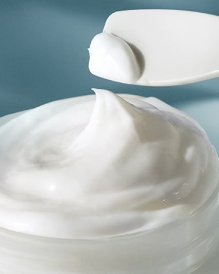 Applicator removing a small amount of the moisturising soft cream from container.